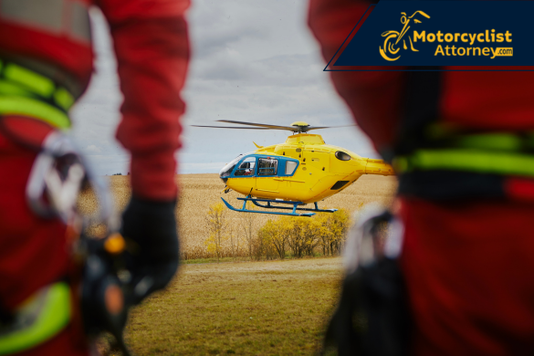 Un helicóptero médico amarillo aterriza en un campo abierto mientras rescatistas observan en primer plano, simbolizando la urgencia de atención tras un accidente grave. La imagen refleja el traslado aéreo de un motociclista con heridas críticas cerca de Pine Mountain Club, como reporta Motorcyclist Attorney.